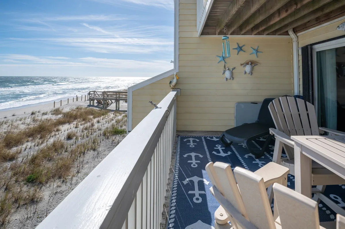 A tranquil balcony setup with comfortable seating and decorative starfish, offering a panoramic view of the ocean. The scene suggests a quiet space for families to unwind and enjoy the outdoors after a day of adventure.