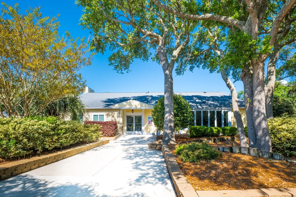 An exterior view of the front entrance framed by large trees and manicured landscaping. The space appears inviting and secure, ideal for welcoming guests and providing a sense of arrival.
